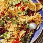 Taco salad in a bowl with spoons on the side.
