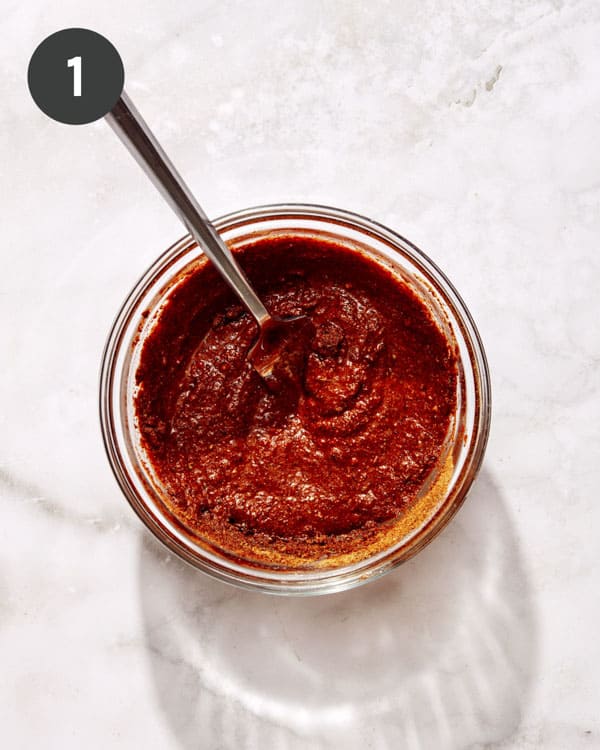 Taco seasoning mixed with water to make paste in a bowl with a spoon.