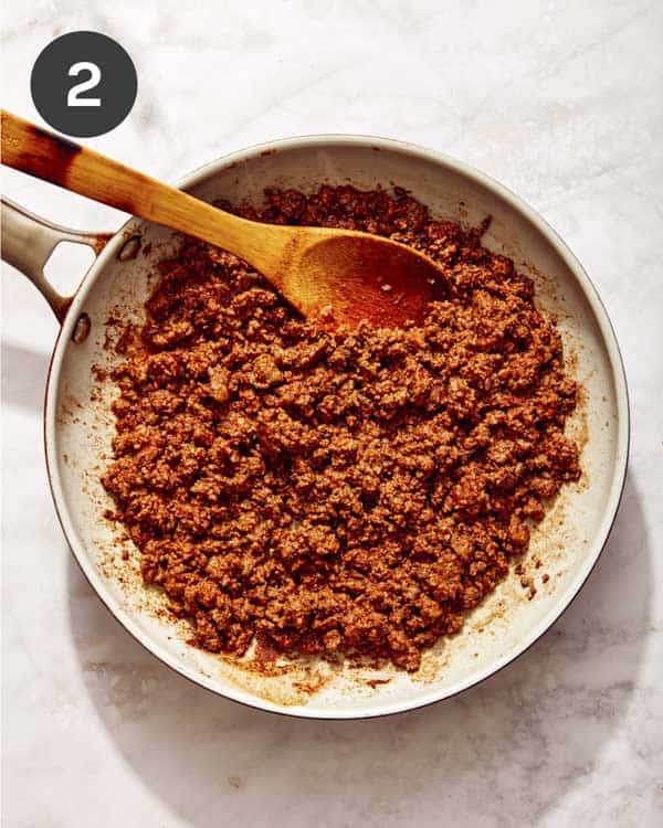 Ground beef in a skillet with taco seasoning cooking.