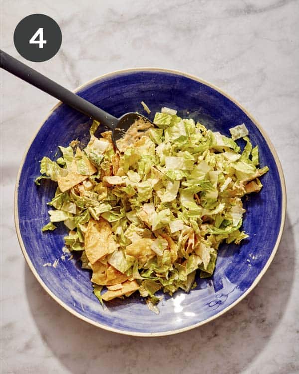 Taco salad tossed with dressing in a big bowl.
