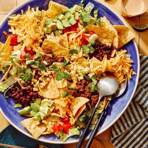 Taco salad in a big bowl with a plate on the side.