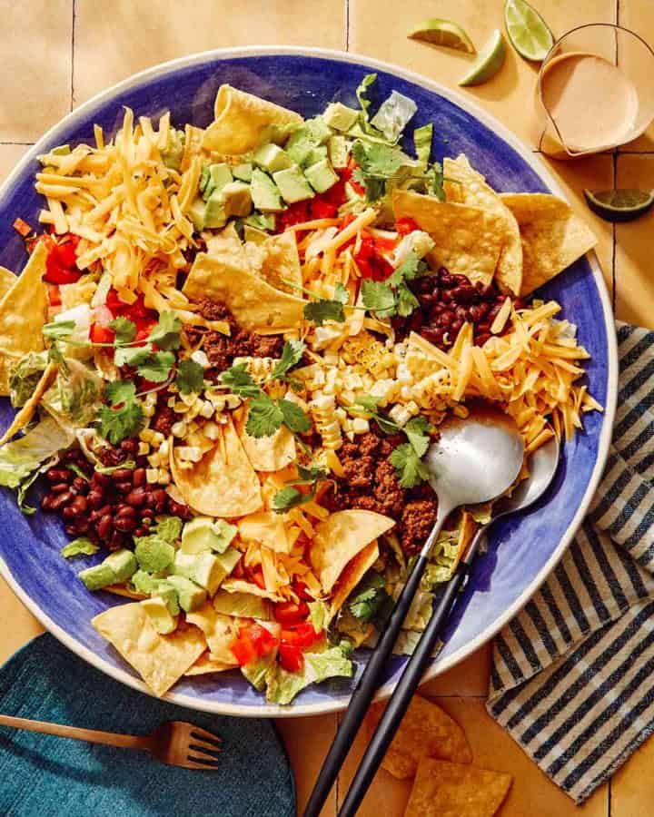 Taco salad in a big bowl with a plate on the side.