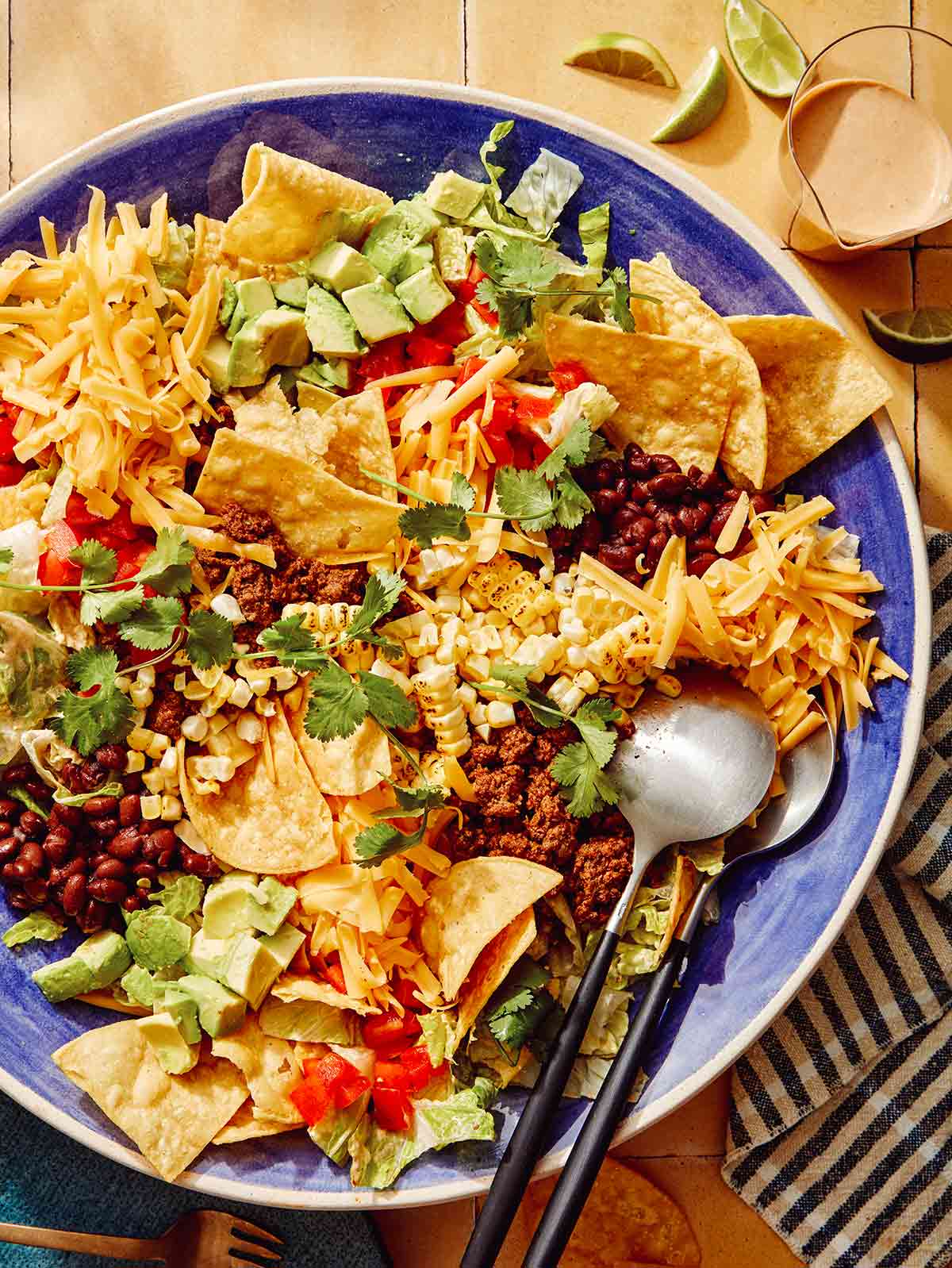 Taco salad in a bowl with spoons on the side.