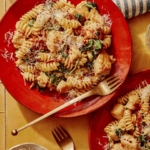 Tuscan chicken pasta on a plate with a fork next to it.