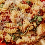 Tuscan chicken pasta on a plate with a fork next to it.
