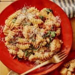Tuscan chicken pasta on a plate with a fork next to it.