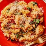 Tuscan chicken pasta on a plate with a fork next to it.