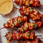 Air fryer bang bang chicken skewers with dipping sauce.