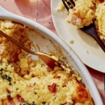 Corn casserole recipe with some scooped out on a plate.