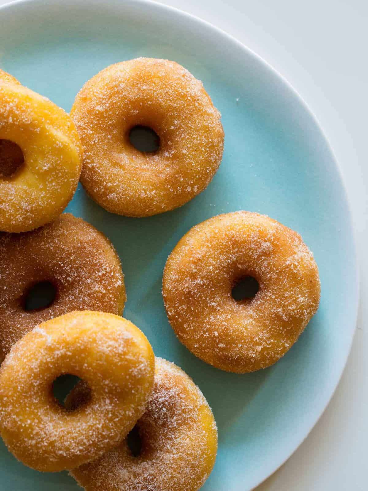 A close up of a plate of sweet potato spudnuts coated with sugar and cinnamon.