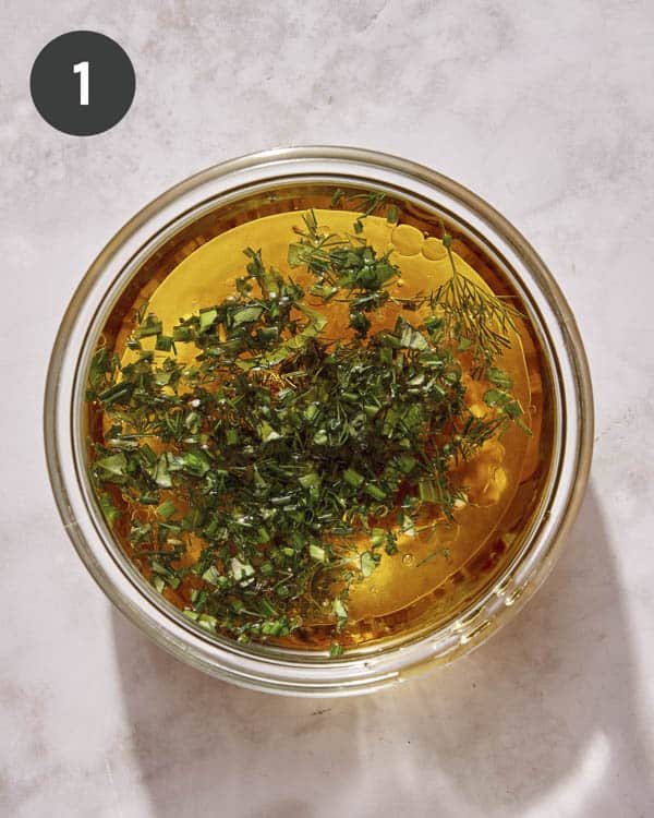 Ingredients for an herb vinaigrette dressing in a glass bowl.