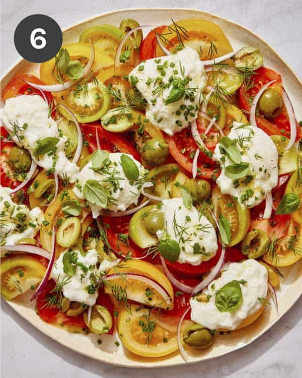 Tomato salad ingredients with an herb vinaigrette poured over it.