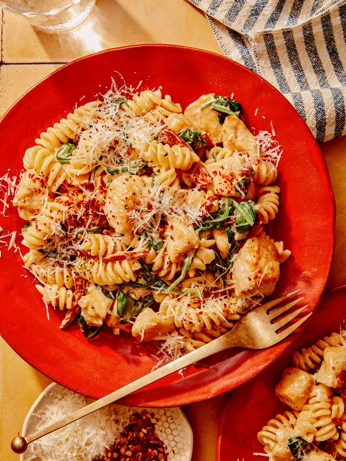 Tuscan chicken pasta on a plate with a fork next to it. 