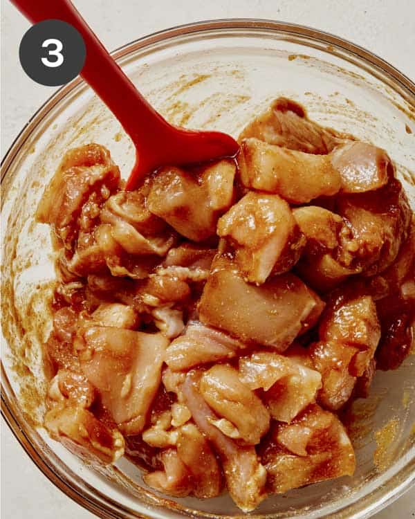 Chicken and marinade in a glass bowl mixed together.