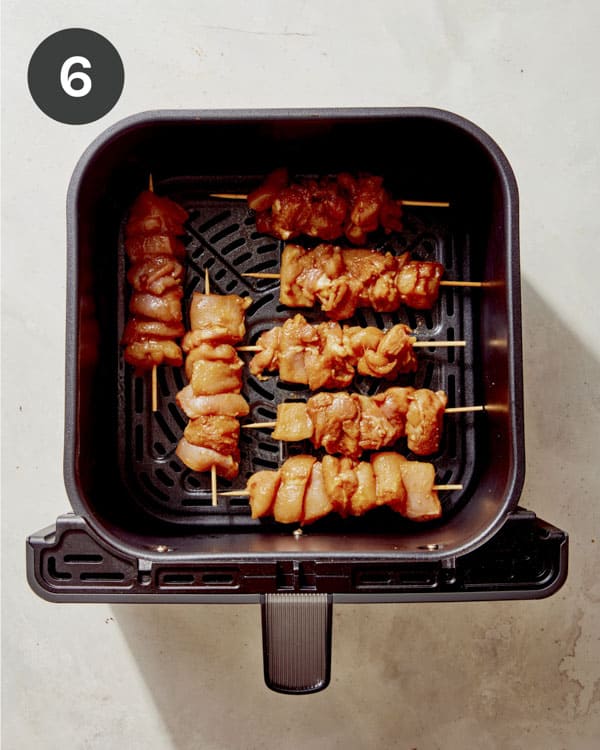 Chicken skewers in an air fryer basket ready to be cooked.
