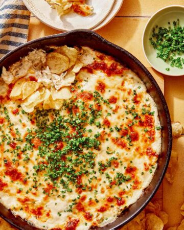 Crab dip recipe in a skillet with potato chips on the side.