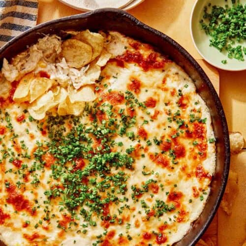 Crab dip recipe in a skillet with potato chips on the side.