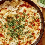 Crab dip recipe in a skillet with potato chips on the side.