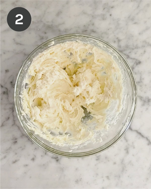 Whipped cream cheese and honey together in a glass bowl.