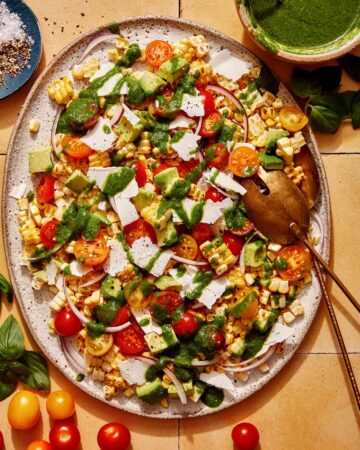 Corn salad on a platter with basil vinaigrette on the side.