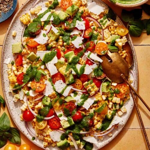 Corn salad on a platter with basil vinaigrette on the side.