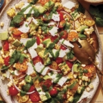 Corn salad on a platter with basil vinaigrette on the side.
