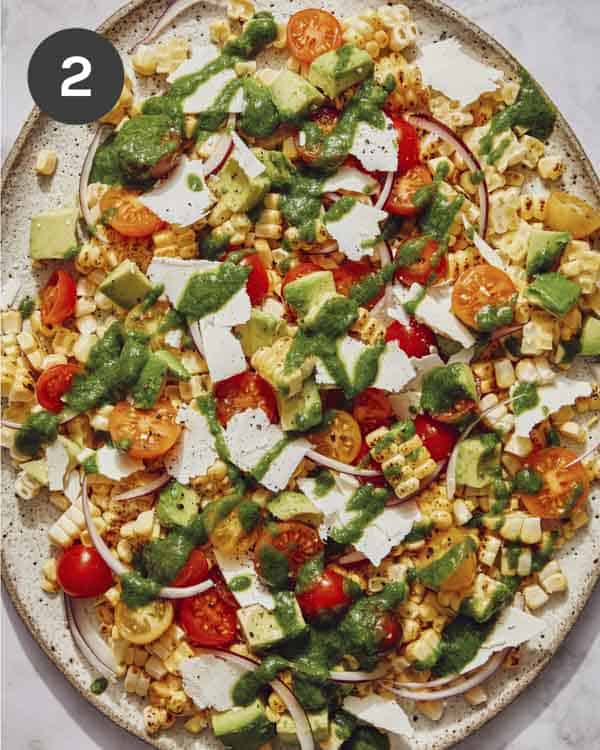 Summer corn salad recipe on a platter with dressing on top. 