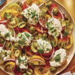Tomato salad on a plate with herbs on the side.