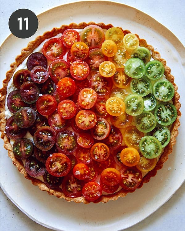 Close up on an ombre tomato tart with different colors of tomatoes.