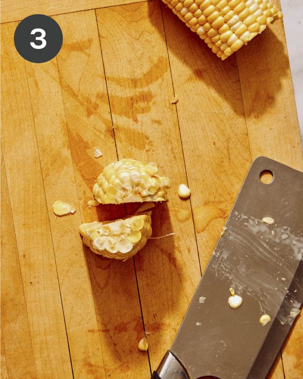 Corn on the cob being cut down the middle.