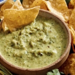 Tomatillo salsa in a bowl with chips being served on the side.