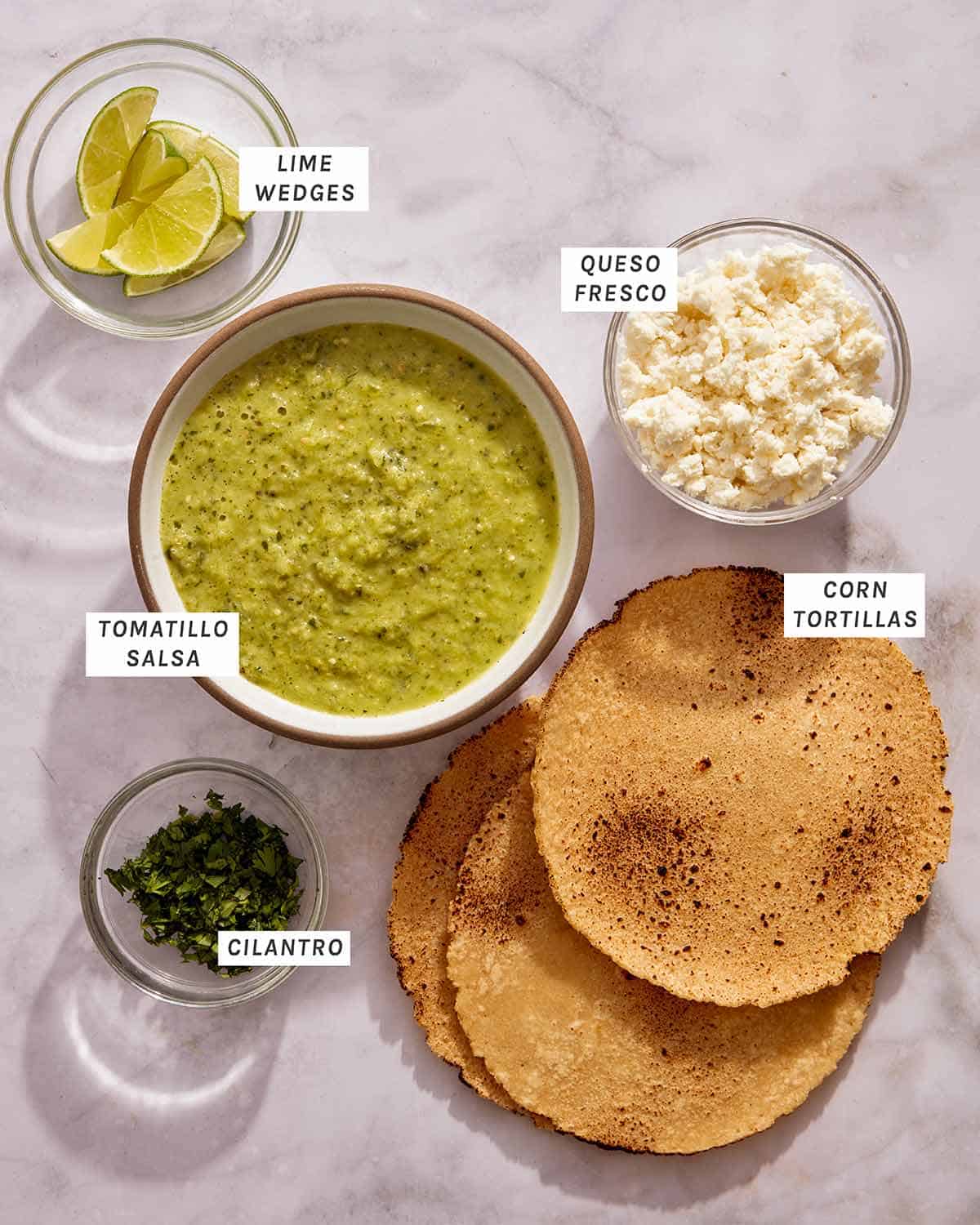 Išdėstyti vegetariškų tacos surinkimo ingredientai.