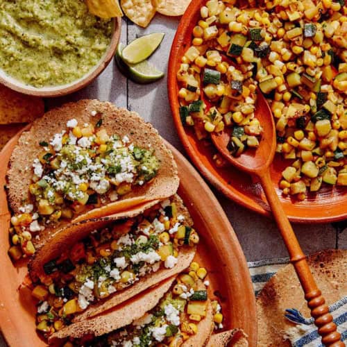 Vegetarian tacos on a platter with the zucchini and corn filling on the side.