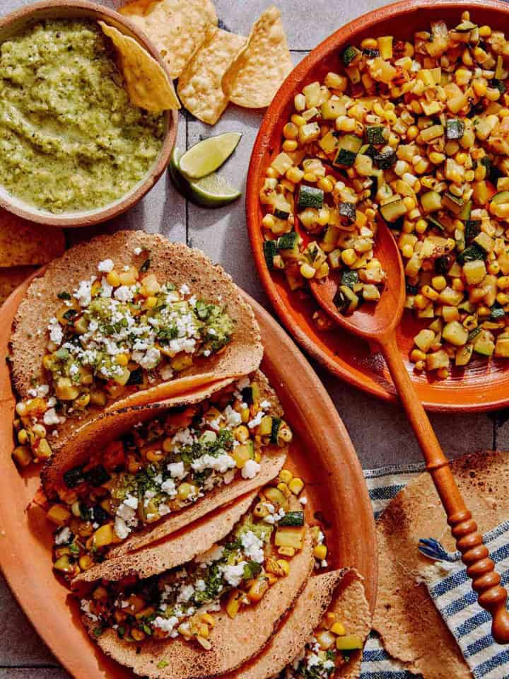 Vegetarian tacos on a platter with the zucchini and corn filling on the side.