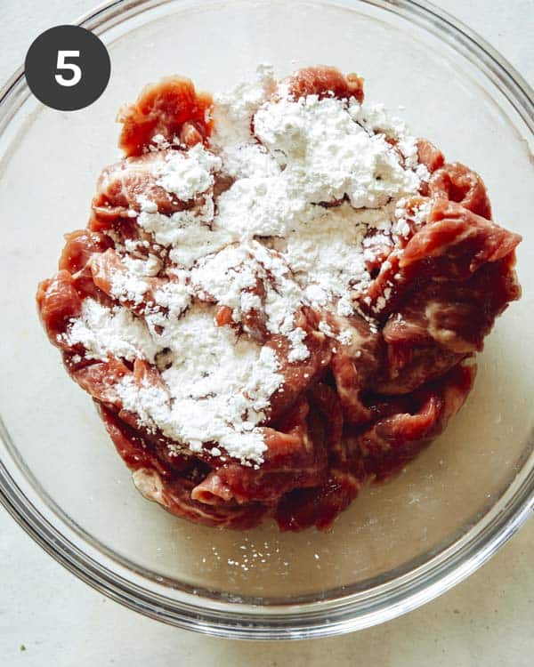Szechuan beef with cornstarch in a glass bowl.