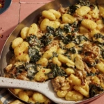 Baked gnocchi in a pan being scooped out to serve.