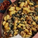 Baked gnocchi with some red pepper flakes on the side.