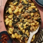 Baked gnocchi with some red pepper flakes on the side.