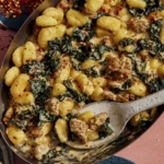 Baked gnocchi being scooped out onto a plate.