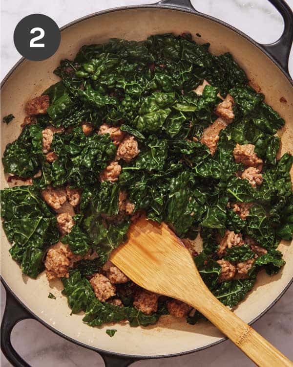 Sausage and kale cooking in a skillet.