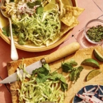 A bowl of soup with a cutting board of garnishes next to it.