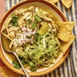 Chicken pozole verde in a bowl with chips on the side.