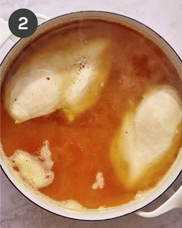 Chicken breast simmering in chicken stock.