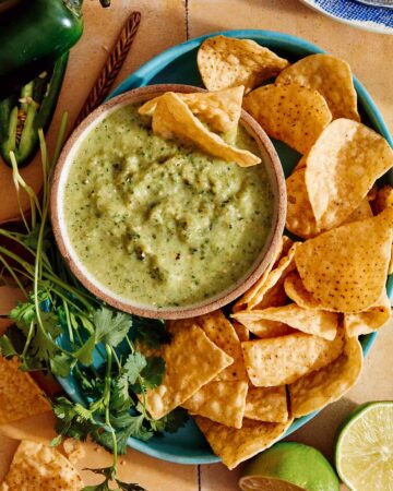 Tomatillo salsa in a bowl with chips on the side.