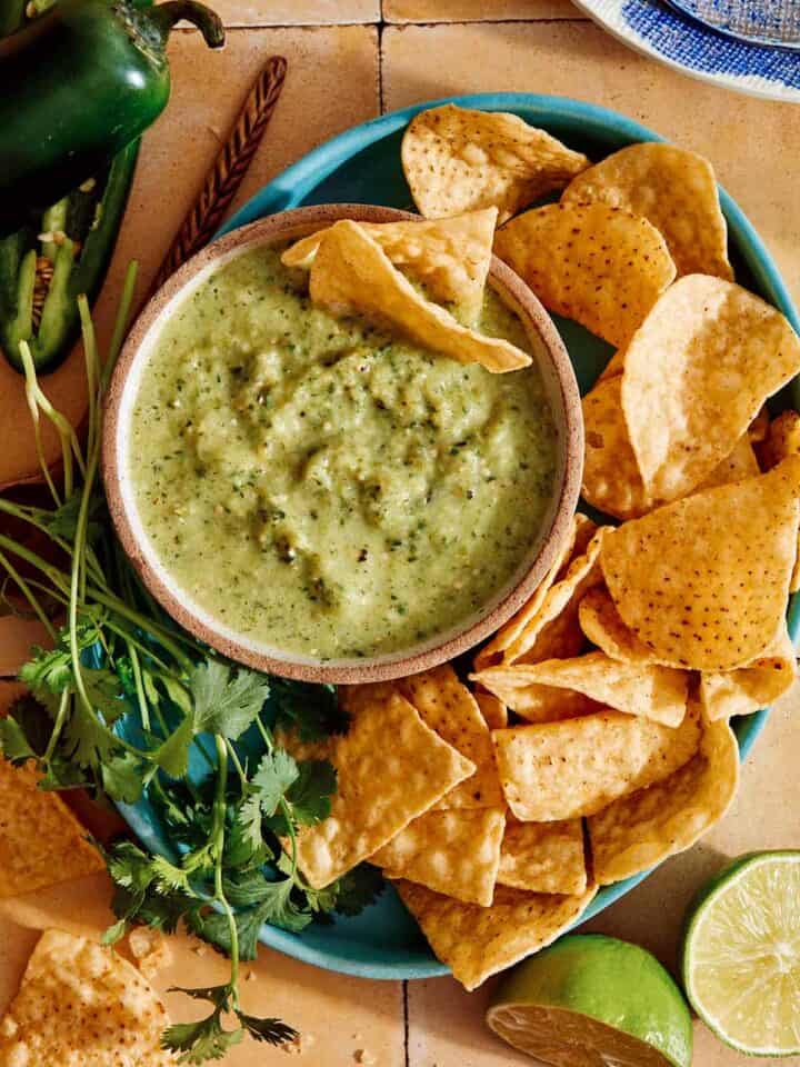 Tomatillo salsa in a bowl with chips on the side.