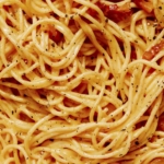 Carbonara in a skillet being tossed.