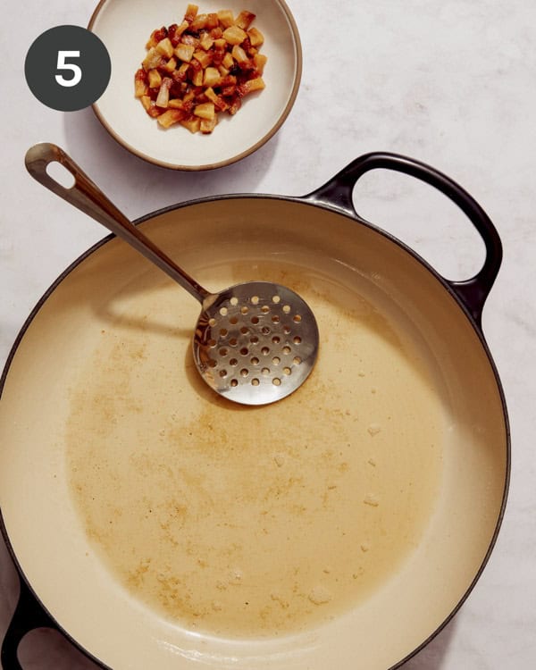 Guanciale being take out of a skillet and set aside.