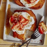 Honey toast being cut into with a fork and knife on a plate.