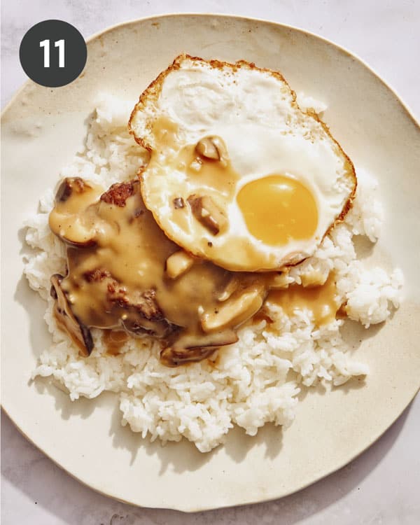 Building a plate of Loco Moco with a fried egg on top.
