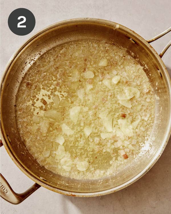 Garlic and shallots being cooked in a pan.